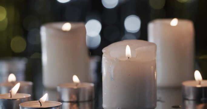 Video of white candles with white flame and copy space with bokeh on black background