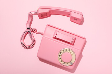 Vintage pink phone on pink background, top view