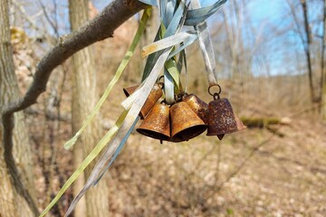 Small metal bells hung in the garden, a sunny spring day, decorated with different colored ribbons