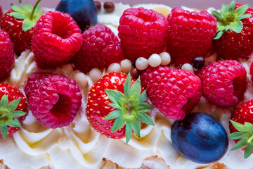 Close up shot of meringue roll Pavlova cake with cream and fresh berries: blueberries, raspberries, strawberries.
