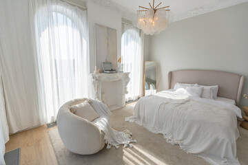 a gentle cozy bright apartment with huge panoramic windows with sunlight. bedroom in soft beige...