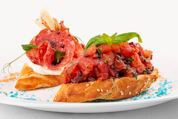 Bruschetta with Italian salami and chopped tomatoes. Isolated image on a white background.