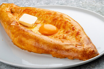 Adjar-style khachapuri with cheese, egg and butter. Caucasian cuisine. Isolated image on a gray background.