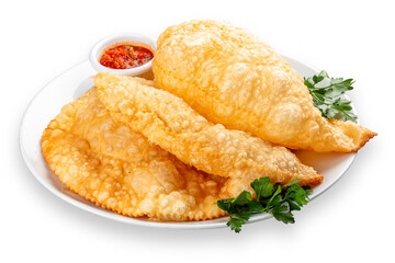 Chebureks with meat, spicy red sauce and greens on a plate. Deep-fried pies made of puff pastry. Isolated image on a white background.