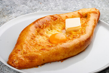 Adjar-style khachapuri with cheese, egg and butter. Caucasian cuisine. Isolated image on a gray background.