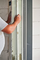 Installing white polystyrene foam board insulation on a bare wall next to window - closeup detail...