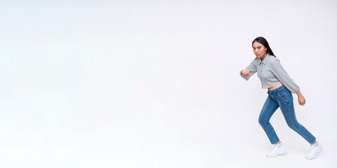 Side view of a dynamic young asian woman running to the left. Wearing casual clothing going at a fast pace. Copy space on the left. Isolated on a white background.