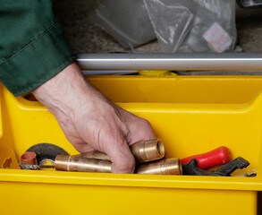 Handwerker holt Fittings aus gelber Toolbox
