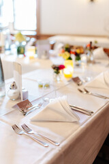 Beautiful table setting and decorations at a wedding. Wedding venue with beautiful decor, flowers, cutlery and lights