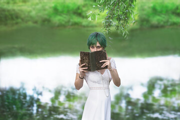 mysterious girl showing her face hidden by a book in the middle of nature