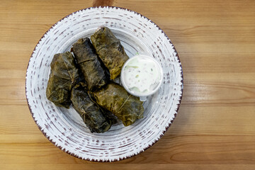 dolma - stuffed grape leaves with meat and rice on a clay plate top view
