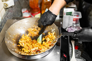 Chef cooking stir fry rice and chicken in wok pan at restaurant kitchen.