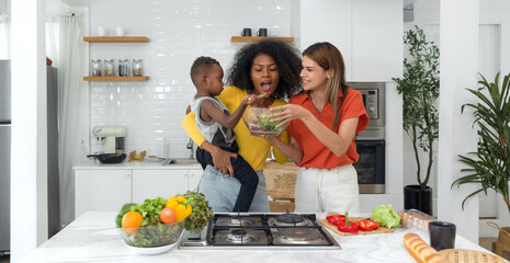 Two women and a child, cooking together in a well-lit, homey kitchen, standing before a modern stove, embodying unity, love and tradition.