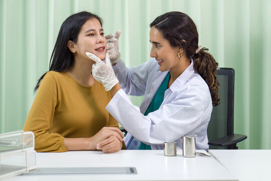 Closeup inspection by dermatologist examining facial skin condition of a young woman under clinical bright light