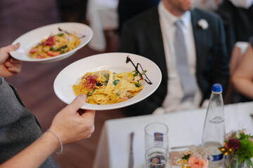 Delicious pasta being brought to the table by the waiter at a wedding