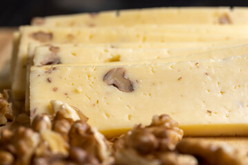 Sliced piece of milk cheese with walnuts