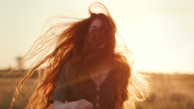 Woman with redhead running to the distance at sunset across the field. 