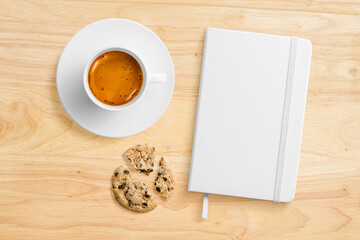 Top view of a blank hardcover leather notebook on a wood office desk table with a cup of coffee and...