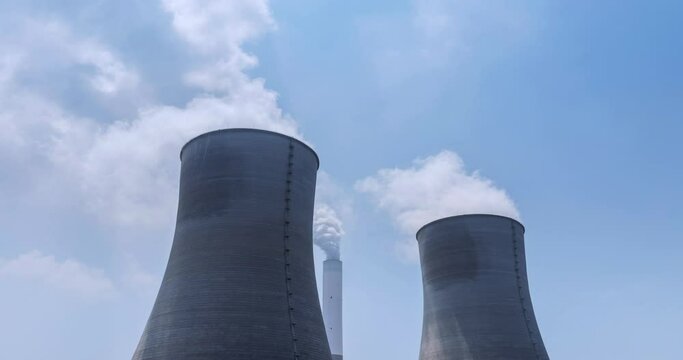 time lapse photography video of water cooling towers, chimney, and steam of coal-fired power plants under blue sky and sunlight, industrial landscape