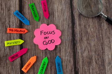 Focus on God, handwritten quote on note and magnifying glass on wooden table. Seek first His...