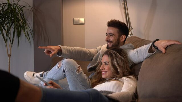 A Caucasian couple sitting on the sofa watching TV in the romantic mode of their home, lifestyle of a couple on a romantic evening. 4k video