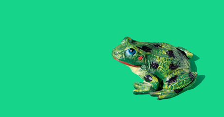 Frog statue on green background. Space for text. Banner. Copy space