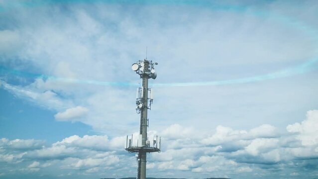 Transmission communication tower with different antennas in front of cloudy blue sky sends digital signals