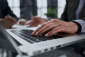 man's hands typing on laptop keyboard in interior