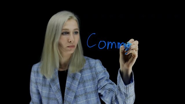 A girl in a jacket writes the word commision on a dark background. Dark background.