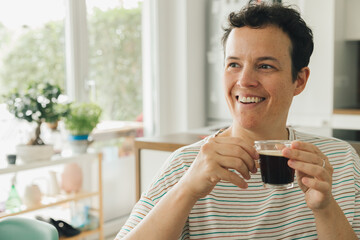 Portrait of a caucasian woman smiling while drinking a cup of coffee at home