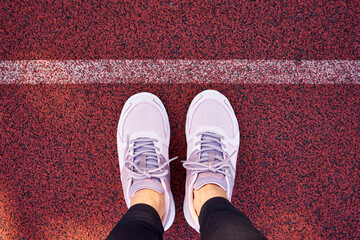 Sports shoes of a woman standing on a running track behind a line