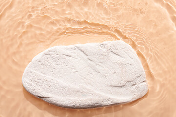 Water beige surface abstract background. Waves and ripples texture of cosmetic aqua moisturizer with bubbles and white product pedestal.