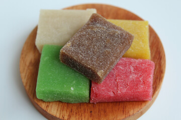 Yangko is traditional snack from Yogyakarta, Indonesia. Made from glutinous rice powder. Colorful yangko on wooden plate, isolated on white background