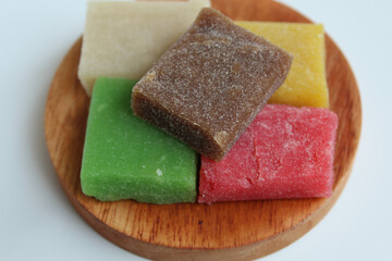 Yangko is traditional snack from Yogyakarta, Indonesia. Made from glutinous rice powder. Colorful yangko on wooden plate, isolated on white background