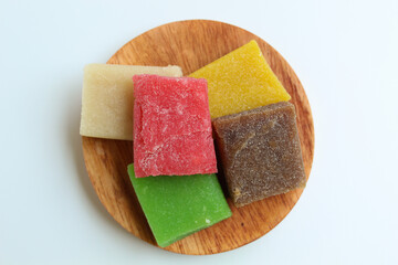 Yangko is traditional snack from Yogyakarta, Indonesia. Made from glutinous rice powder. Colorful yangko on wooden plate, isolated on white background. Flat lay or top view