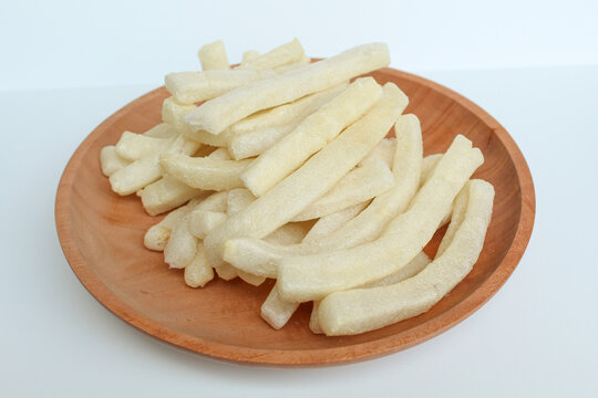 Kerupuk panjang, Indonesian snack or food condiment. Fried tapioca flour in long thin shape. On wooden plate, isolated on white background