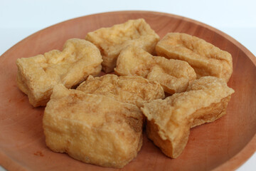 Fried tofu on wooden plate, on white background