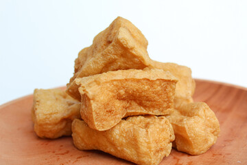 Fried tofu on wooden plate, on white background
