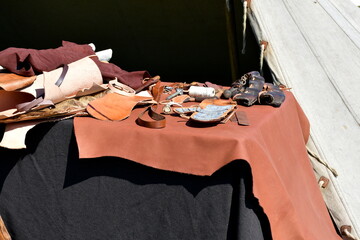 A close up on a set of items belonging to a medieval merchant or blacksmith displayed on a linen cloth located next to a cloth tent seen during a medieval festival or fair oraganized in Poland 