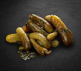 Pickled cucumbers, handmade pickles on dark stone background.