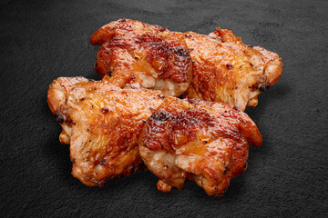Grilled chicken thighs, handcrafted on a dark stone background. BBQ menu