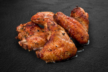 Grilled chicken wings on a dark stone background. BBQ menu
