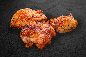 Grilled chicken thighs, handcrafted on a dark stone background. BBQ menu