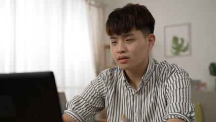 tired asian businessman suffering a blurred vision is still having trouble seeing clearly after massaging his eyes while working from home on the computer.
