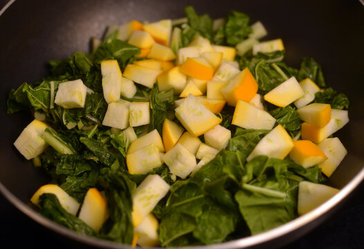 A pan with chopped chard and zucchini detail view