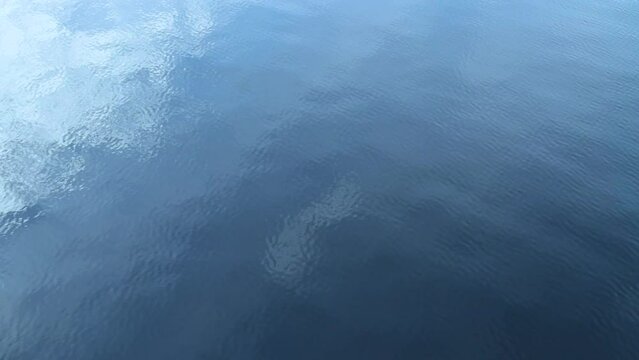 Blue river water surface with ripples and light reflection.