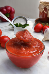 Fresh tomatoes, basil and tomato sauce with spoon on the light table. Side view. 