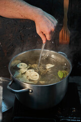A large metal saucepan on the stove. stir the dumplings in water during cooking