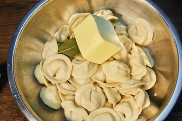 Ready-cooked dumplings in a bowl with spices and butter.