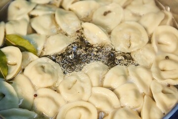 A large metal saucepan on the stove. The process of cooking dumplings